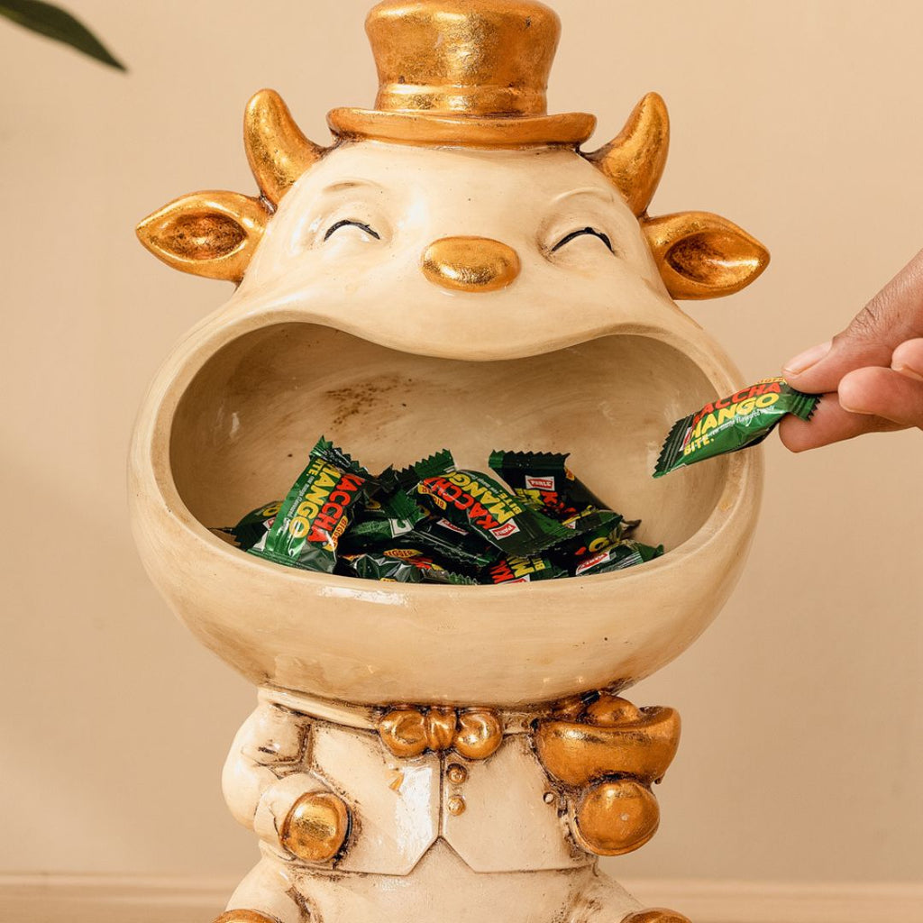 a statue of a cow holding a candy bar in it's mouth